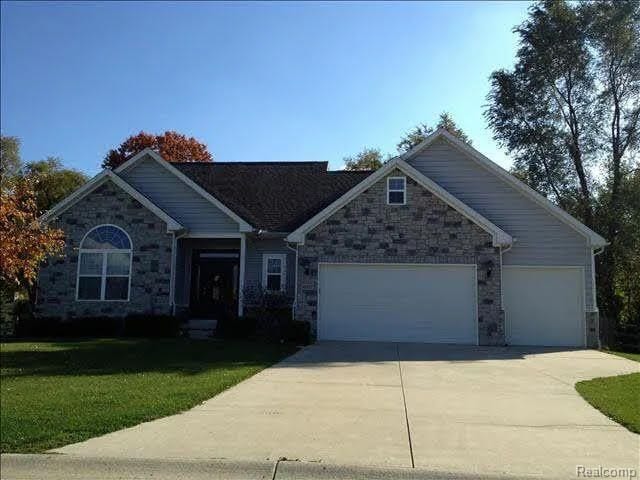 14922 Wildwood Dr, Monroe, MI 48161 - view of front of home with a garage, a front yard, concrete driveway, and stone siding