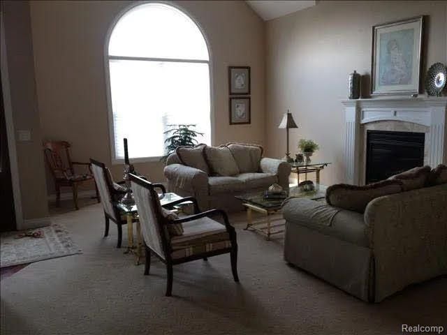 14922 Wildwood Dr, Monroe, MI 48161 - living room with a glass covered fireplace, vaulted ceiling, and carpet floors