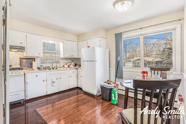 3817 Boone Ave SW, Wyoming, MI 49519 - kitchen with white appliances, under cabinet range hood, white cabinets, a sink, and dark wood-type flooring