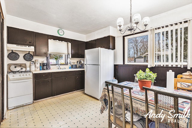 3817 Boone Ave SW, Wyoming, MI 49519 - kitchen with light countertops, under cabinet range hood, light floors, white appliances, and a notable chandelier