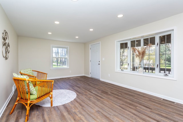 living area with baseboards, visible vents, dark wood-type flooring, and recessed lighting