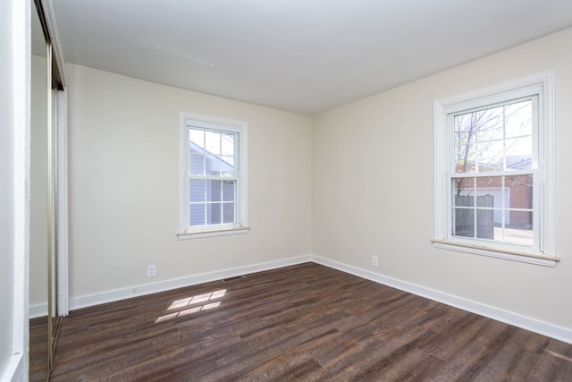unfurnished room with dark wood finished floors and baseboards