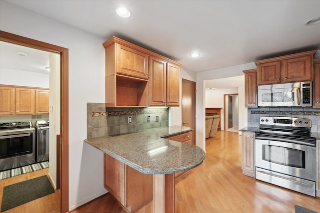 29691 Sierra Pointe Cir, Farmington Hills, MI 48331 - kitchen featuring light stone countertops, appliances with stainless steel finishes, light wood finished floors, decorative backsplash, and washing machine and dryer