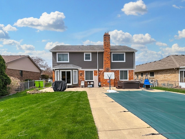 back of property featuring a chimney, a fenced backyard, a hot tub, a patio, and a lawn