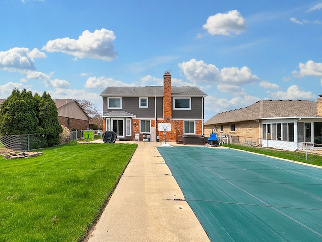 back of house featuring a fenced backyard, a hot tub, a fenced in pool, and a lawn