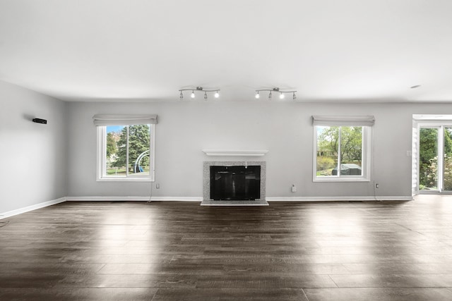 unfurnished living room featuring dark wood-style floors, a wealth of natural light, and a premium fireplace