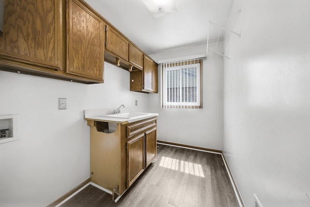 laundry area with hookup for a washing machine, cabinet space, dark wood finished floors, and a sink