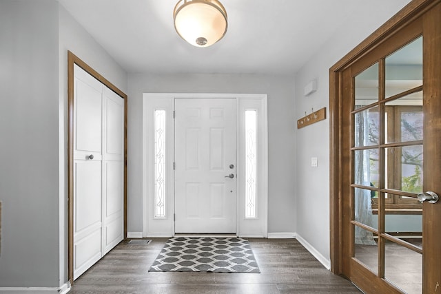 foyer entrance with a wealth of natural light, dark wood finished floors, and baseboards