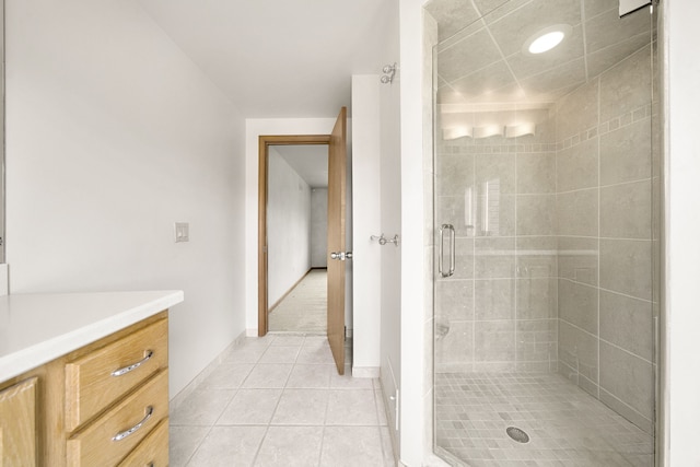 full bathroom with a stall shower, tile patterned flooring, vanity, and baseboards