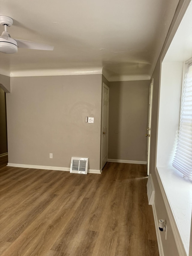 empty room featuring baseboards, visible vents, wood finished floors, and a ceiling fan