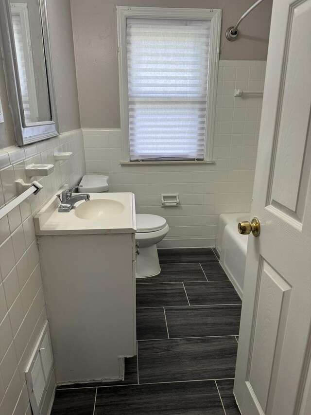 bathroom featuring shower / tub combination, a wainscoted wall, toilet, tile walls, and vanity