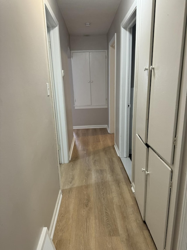 corridor featuring light wood-style flooring and baseboards
