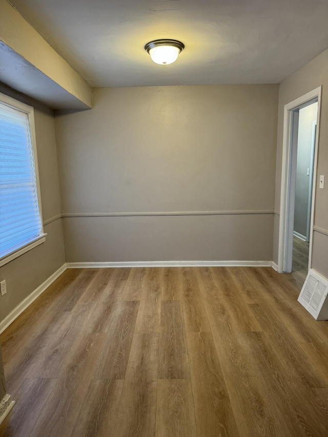 unfurnished room with visible vents, wood finished floors, and baseboards