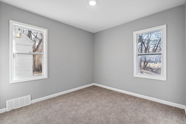 carpeted empty room featuring visible vents, a wealth of natural light, and baseboards