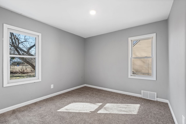 unfurnished room featuring carpet, visible vents, and baseboards