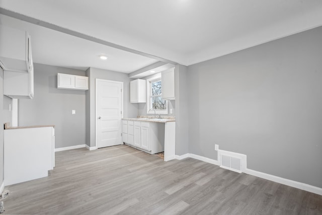interior space with a sink, visible vents, baseboards, recessed lighting, and light wood finished floors