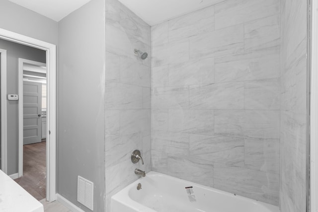 full bath with baseboards, visible vents, wood finished floors, and tub / shower combination