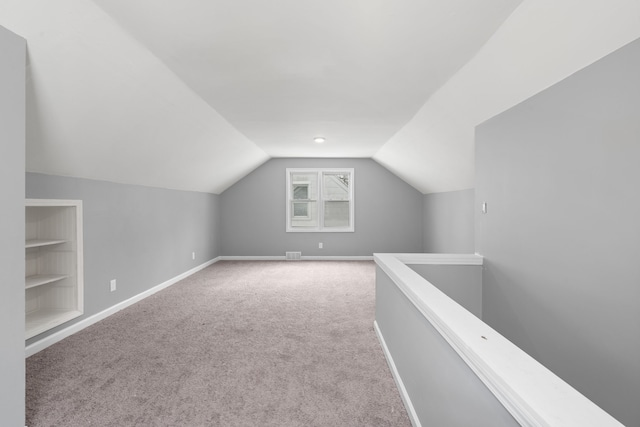 additional living space with baseboards, visible vents, carpet floors, and vaulted ceiling