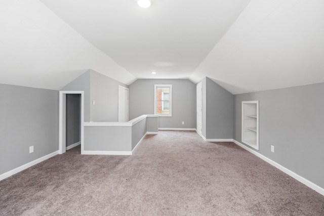 bonus room with built in shelves, lofted ceiling, carpet floors, and baseboards