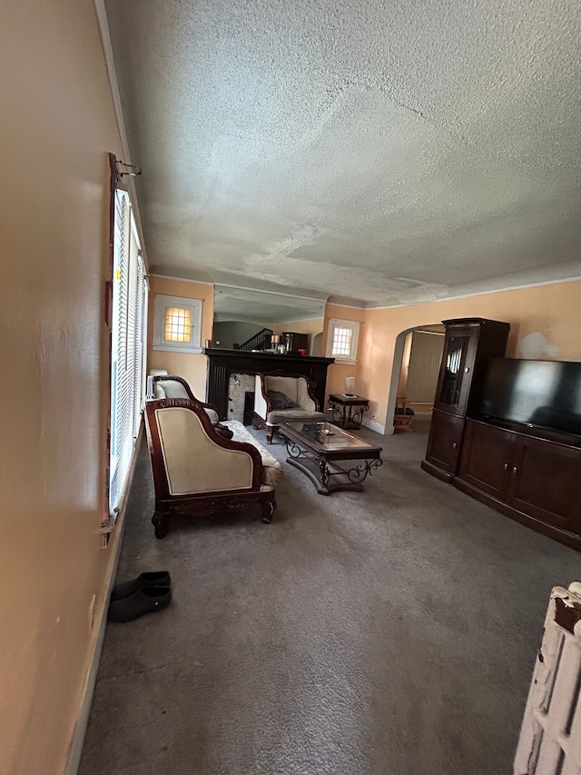 carpeted living area featuring a textured ceiling, baseboards, and arched walkways
