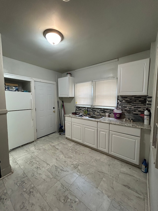 kitchen with decorative backsplash, white cabinets, a sink, freestanding refrigerator, and marble finish floor