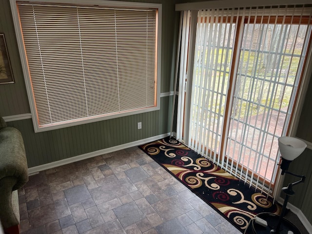 doorway to outside featuring stone finish floor and baseboards