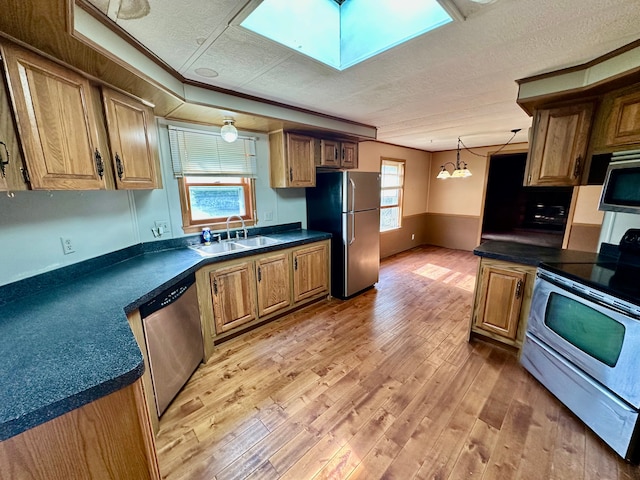 1088 Kern Rd, Fowlerville, MI 48836 - kitchen with stainless steel appliances, a sink, light wood-style flooring, a textured ceiling, and dark countertops
