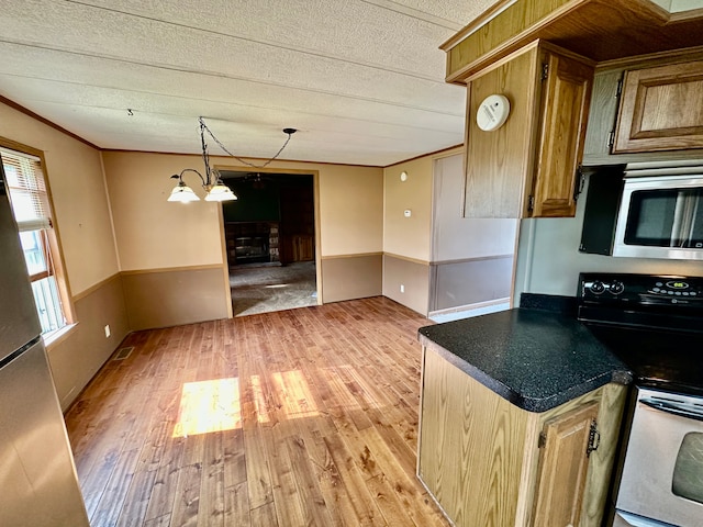 1088 Kern Rd, Fowlerville, MI 48836 - kitchen featuring appliances with stainless steel finishes, light wood-type flooring, ornamental molding, dark countertops, and brown cabinetry