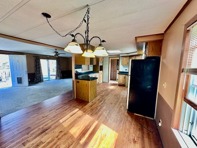 1088 Kern Rd, Fowlerville, MI 48836 - kitchen with freestanding refrigerator, dark countertops, open floor plan, light wood finished floors, and brown cabinets