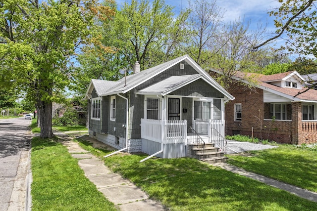 203 E Stewart Ave, Flint, MI 48505 - bungalow with covered porch, a front yard, a chimney, and roof with shingles