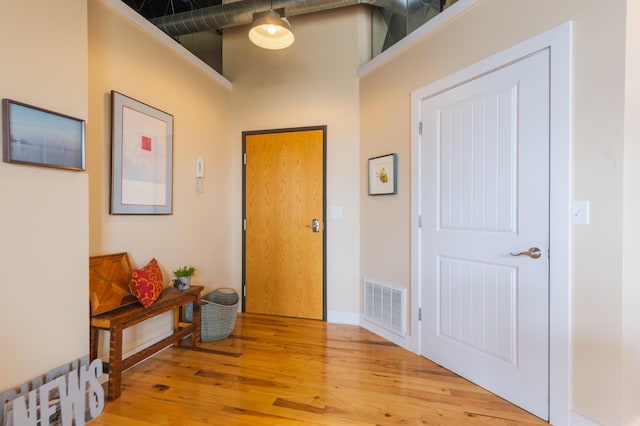 foyer with a high ceiling, visible vents, hardwood / wood-style flooring, and baseboards