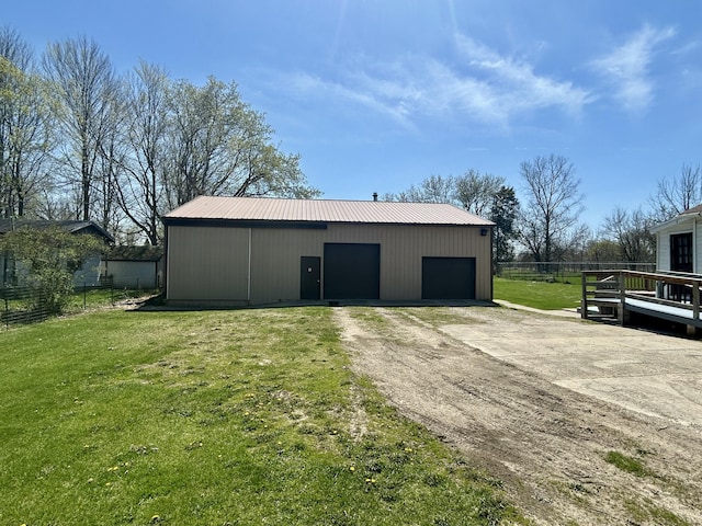 view of pole building with a lawn, driveway, and fence