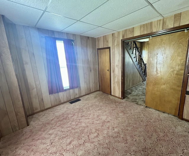 empty room featuring visible vents, stairs, carpet, and a paneled ceiling