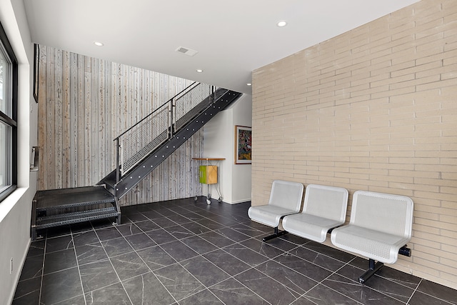 lobby featuring stairway, recessed lighting, and brick wall