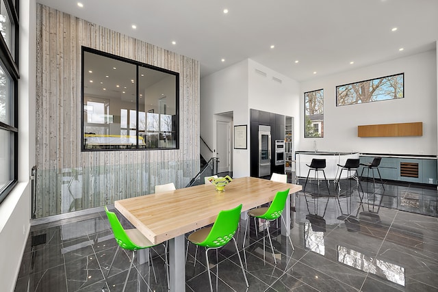 dining area with recessed lighting, stairway, marble tiled flooring, and a high ceiling
