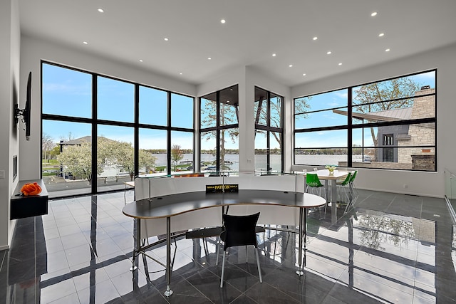 dining area with recessed lighting, a high ceiling, inlaid floor details, baseboards, and a water view
