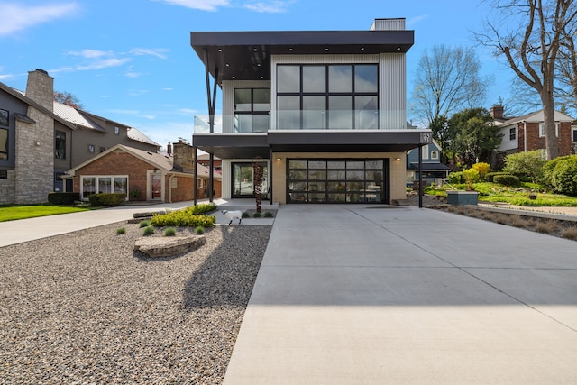 modern home featuring concrete driveway, an attached garage, and a balcony