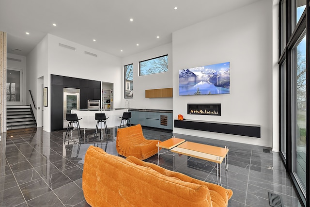 living room with a high ceiling, a glass covered fireplace, and recessed lighting