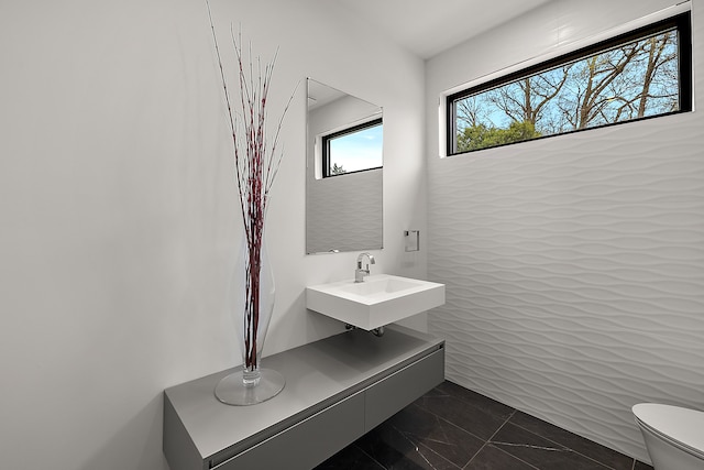 bathroom with a sink, toilet, and marble finish floors