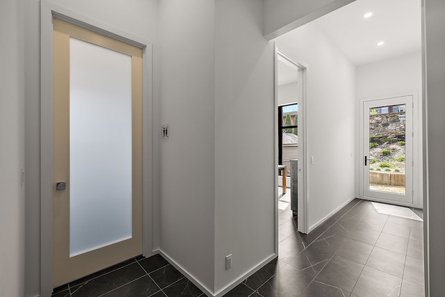 corridor with baseboards, recessed lighting, and dark tile patterned floors