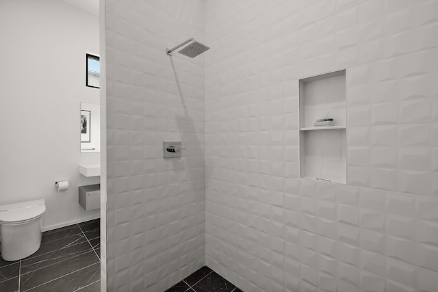 full bathroom featuring tiled shower, toilet, and baseboards