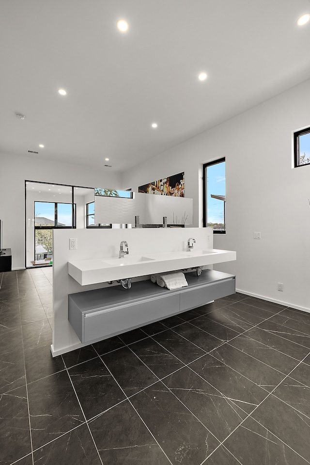 bathroom with recessed lighting, plenty of natural light, baseboards, and double vanity