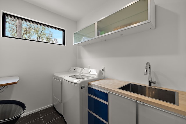 clothes washing area featuring washing machine and dryer, dark tile patterned flooring, and baseboards
