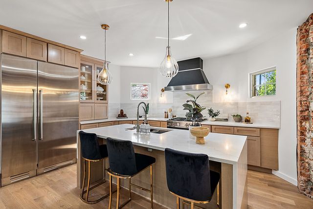 2423 Chicago Blvd, Detroit, MI 48206 - kitchen featuring wall chimney range hood, a sink, light wood-style floors, stainless steel appliances, and light countertops