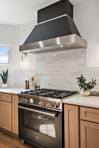 2423 Chicago Blvd, Detroit, MI 48206 - kitchen featuring tasteful backsplash, high end stainless steel range, light countertops, dark wood-style floors, and wall chimney exhaust hood