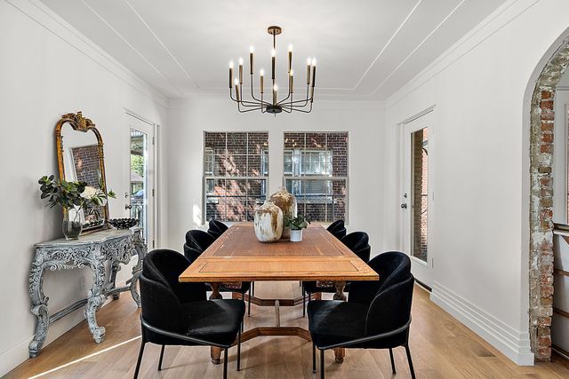 2423 Chicago Blvd, Detroit, MI 48206 - dining area with crown molding, light wood-style floors, a chandelier, baseboards, and arched walkways