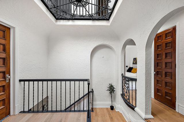 2423 Chicago Blvd, Detroit, MI 48206 - hallway featuring an upstairs landing, wood finished floors, a textured wall, and a notable chandelier