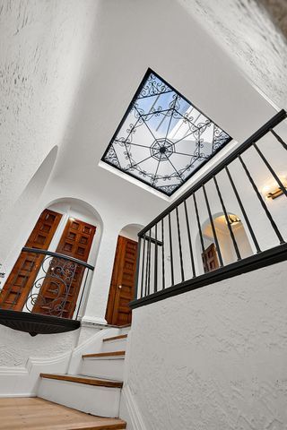 2423 Chicago Blvd, Detroit, MI 48206 - stairs with a towering ceiling, arched walkways, a textured wall, and wood finished floors
