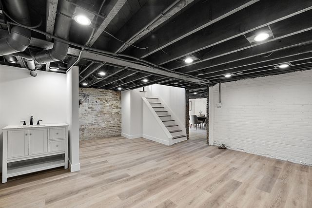 2423 Chicago Blvd, Detroit, MI 48206 - finished basement with brick wall, stairs, light wood-style flooring, and a sink