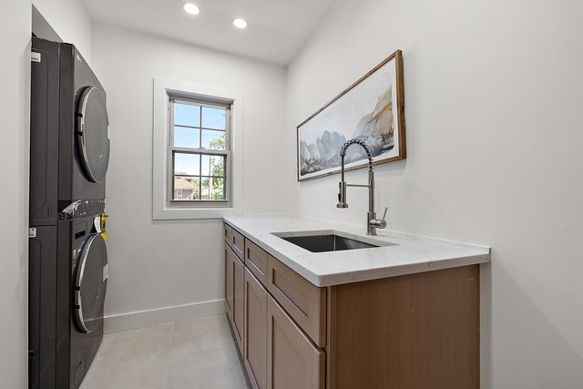 2423 Chicago Blvd, Detroit, MI 48206 - laundry area with stacked washer and dryer, a sink, baseboards, recessed lighting, and cabinet space